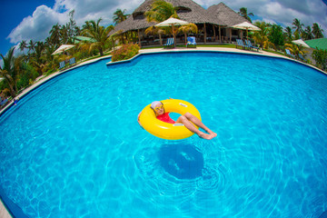 Little happy adorable girl in outdoor swimming pool