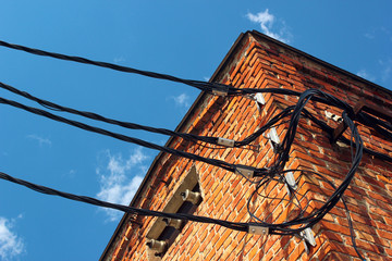 Three powerline insulators and wires on brick wall of old electrocal substation