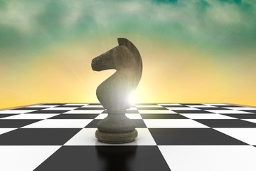 Composite image of black knight on chess board