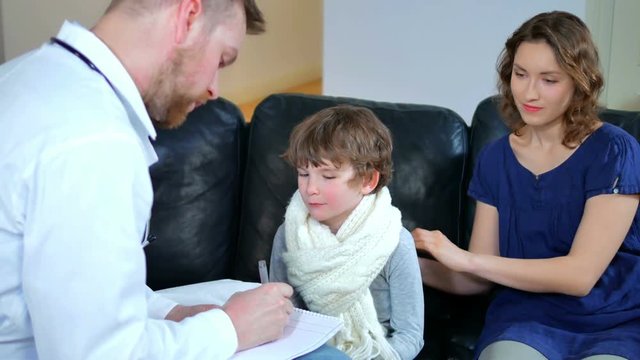 home doctor came to sick boy and his mother. he examines a child and records readings in notebook