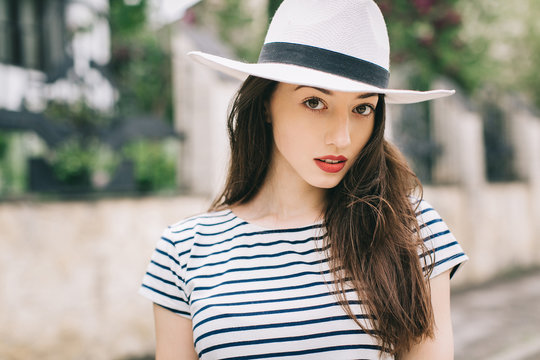 Portrait of a beautiful stylish and fashionable girl in hat on a street.