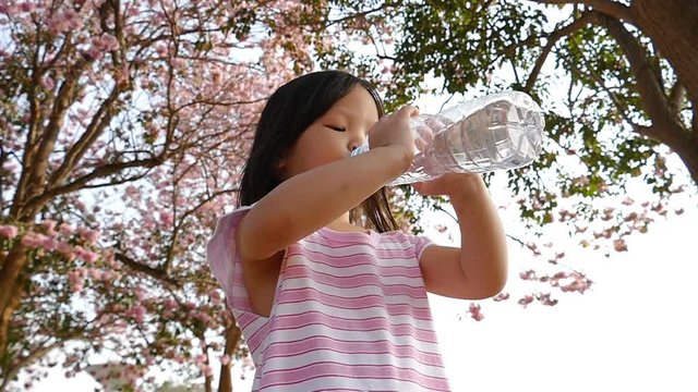 Adorable girl in beautiful dress drink water from bottle
