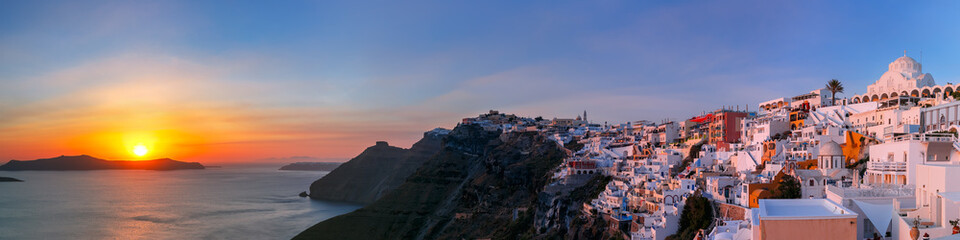 Picturesque panorama of Fira, main town of the island Santorini, sea, white houses and church at sunset, Greece