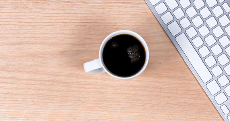 Dark coffee with keyboard on red oak desktop background