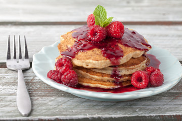 Front view - Whole wheat oatmeal pancakes with boysenberry sauce topped with red raspberries and a mint sprig