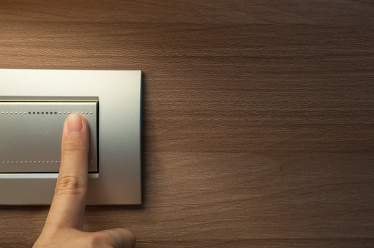 finger is turning on a grey light switch.