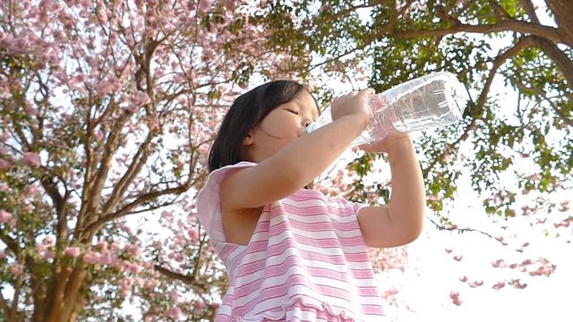 Adorable girl in beautiful dress drink water from bottle
