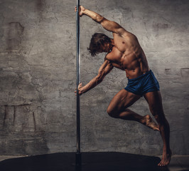 Shirtless man pole dancing.