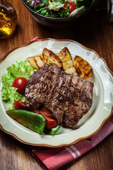Portions of grilled beef steak with grilled potatoes and paprika