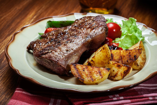 Portions of grilled beef steak with grilled potatoes and paprika