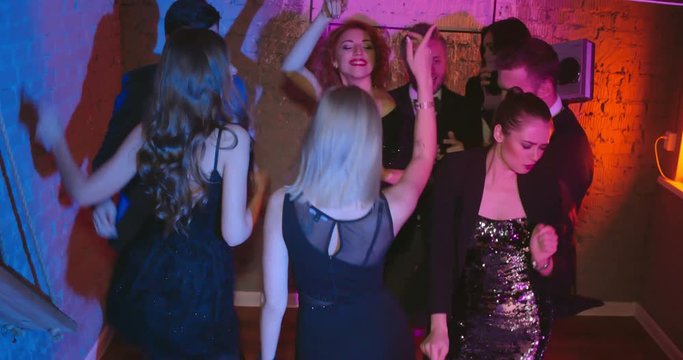 Friends dancing at the party and pushing three girls, they falling down on the floor and laughing