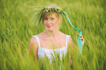 young woman with wreath on his head in a wheat field - 110130797
