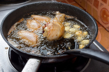 Chicken frying in a pan.