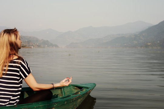 Young Woman meditating on Mountain Lake outdoor. Yoga Meditation position, relax and enjoy nature