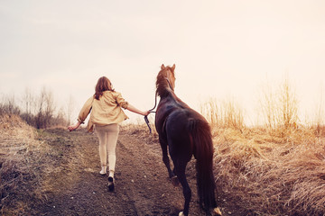 Beautiful young female walking and hugging with her brown hors outdoor without a saddle and bridle - obrazy, fototapety, plakaty
