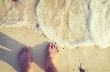 Leisure in summer relax on beach - Above of man's foot with tattoo. retro filter effect