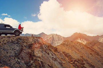 Happy Traveler man sitting on his car on mountains top. 4x4 travel trekking