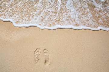 Footprints on sea shore. Sea water wave. Beach Vacation