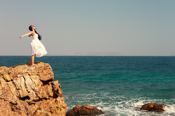 Fototapeta premium Happy girl standing outdoor on edge cliff sea shore. Happiness and freedom enjoy