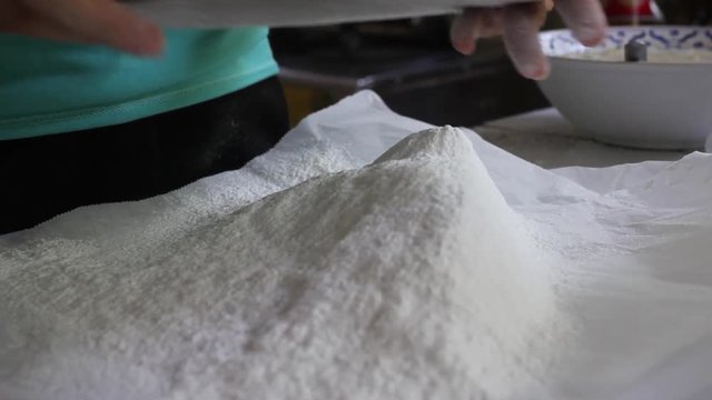 young woman in green shirts ifting flour in the kitchen