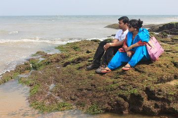 Couple sitting on beach and holding their hands. They loving each other silently.