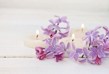 Candles and fresh lilac flowers. Soft light, soft focus.