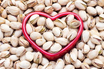 Roasted pistachio nuts with Red Heart on wooden table background