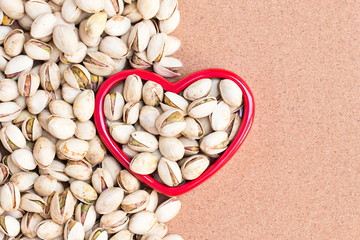 Roasted pistachio nuts with Red Heart on wooden table background