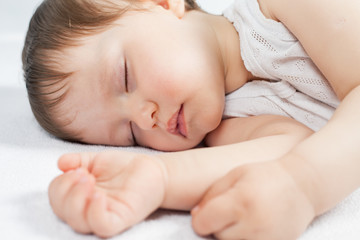 Newborn baby sweet sleeping on a white bed