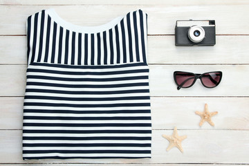 striped t-shirt with sunglasses and a camera with  sea stars on wooden white background