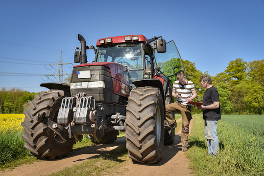 Landwirtschaft - Landwirt mit seinem Sohn bei einer Besprechung am Traktor