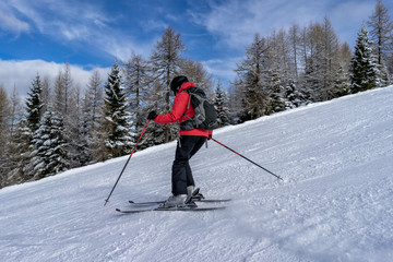 Fototapeta na wymiar Female skier dressed in red jacket enjoys slopes in Italy. Folgaria, Trentino, Italy.