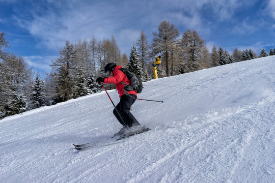 Female skier dressed in red jacket enjoys slopes in Italy. Folgaria, Trentino, Italy.