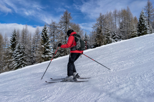 Female skier dressed in red jacket enjoys slopes in Italy. Folgaria, Trentino, Italy.
