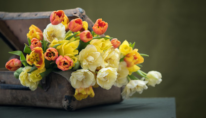 A bunch of beautiful flowers in an old shabby suitcase. On the g