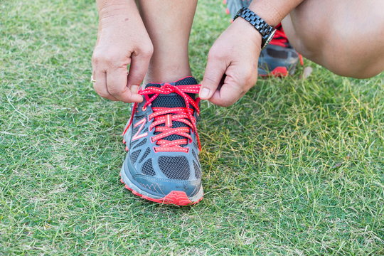 Close up of feet of a runner tying shoe laces in green grass