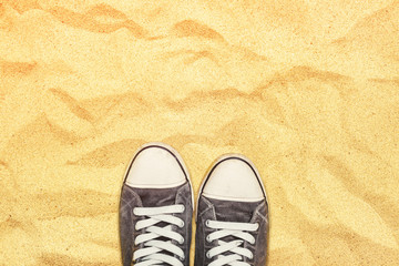 Feet in sneakers standing on war desert sand