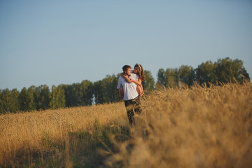 Naklejka na ściany i meble romantic happy couple go on a wheat field.