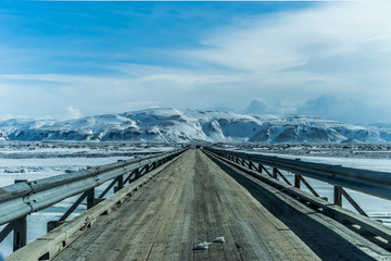 Wooden bridge through snow covered plain in south-western Iceland, near Hekla volcano