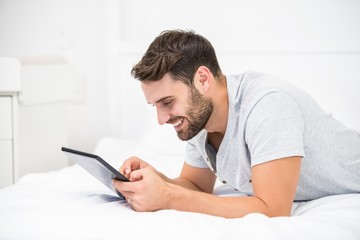 Man using digital tablet on bed