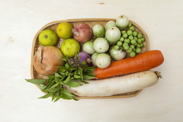Fresh vegetables in the rattan basket on wood background