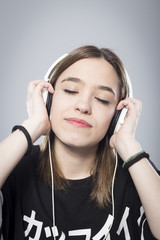 Retrato de chica escuchando música sobre fondo gris 