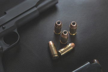 .45 Caliber hollow point bullets near handgun and magazine on le