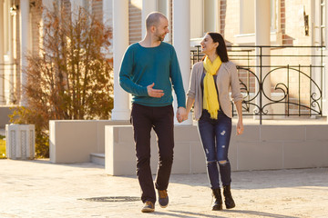 Young couple man and woman walking on the street talking to each other strong back light