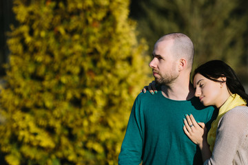 Fototapeta premium Loving young calm and serious couple sitting arm in arm with copy space