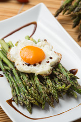 Asparagi verdi con uovo al tegamino su un piatto in ceramica bianco  ambientato