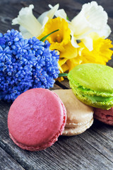 French colorful macarons on a wooden background. Bouquet of daffodils, bouquet of muscari