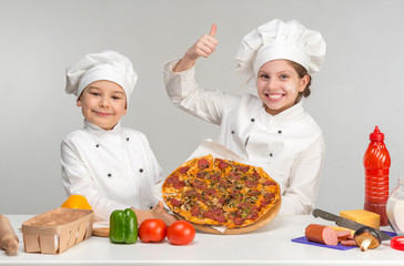 boy and girl in white uniform by the table with pizza