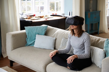 Obraz premium Woman Sits On Sofa At Home Wearing Virtual Reality Headset