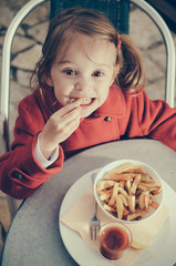 Cute smiling girl eating fries and tomato - Top view